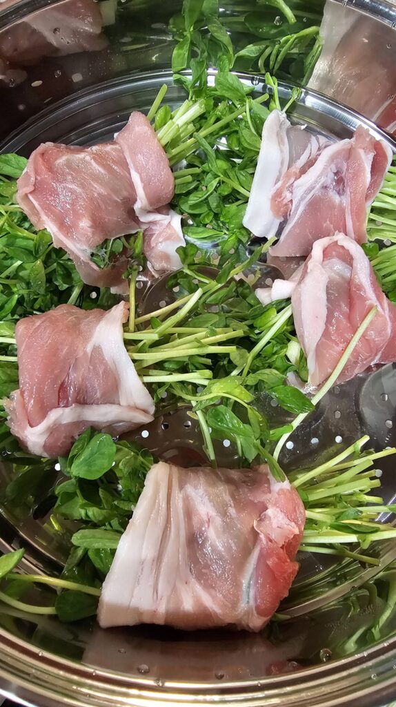 二つの蒸し段に、肉で野菜を巻いたものと、なすを並べた調理前の様子