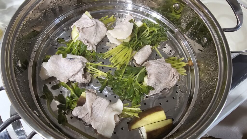 蒸し器に入れた肉巻きと葉物野菜、なすの加熱後の様子
