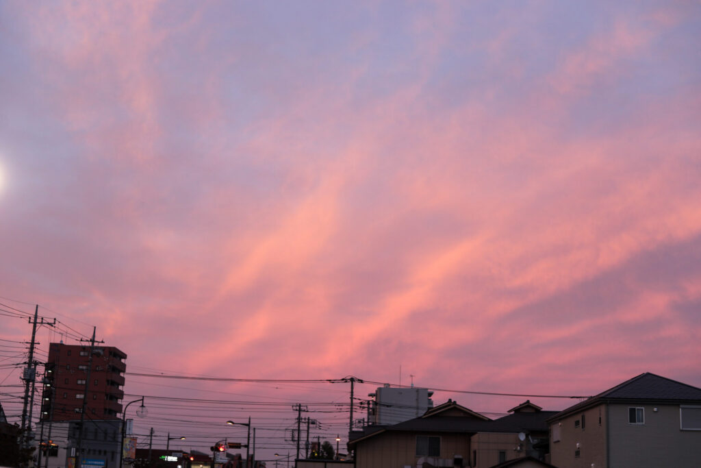 夕焼け空の写真。 太陽の温かさとひんやりとした夜の空気が溶け合うように、オレンジと紫が入り交じっている空。